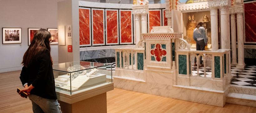 A women looking at case with objects in it in a large gallery.