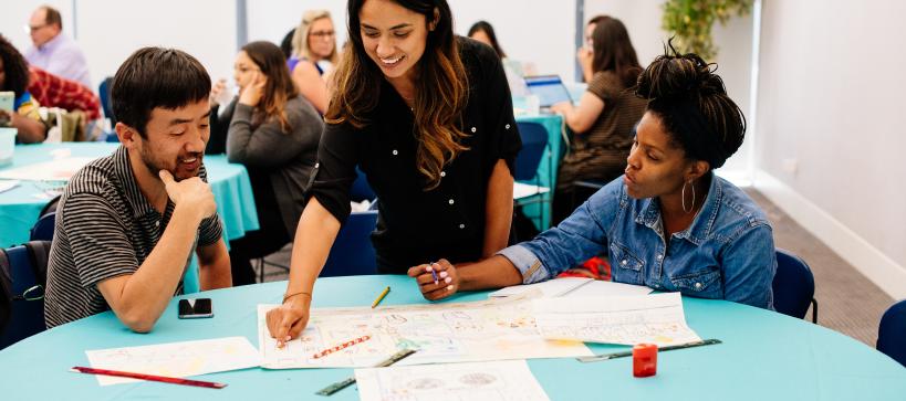 Three educators sit at a table participating in an art project.