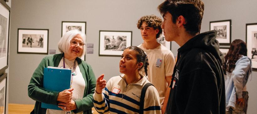 A docent leading a group of young adults through a gallery