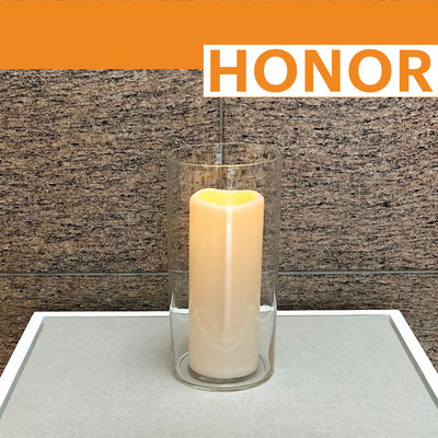 Lit yahrzeit candle on display with word &quot;HONOR&quot;