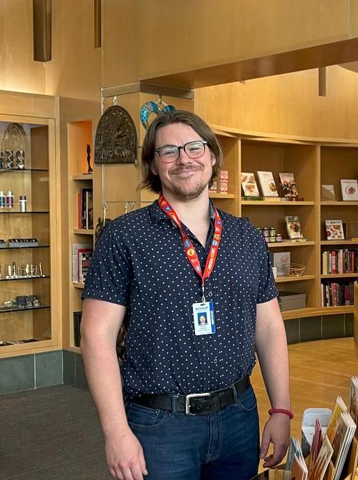 A man stands smiling in a gift store with books behind him.