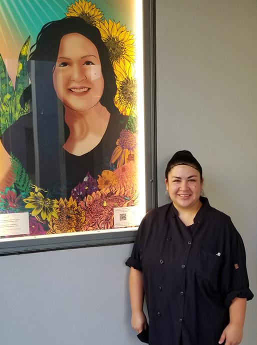 A woman stands next to a framed illustration of herself.