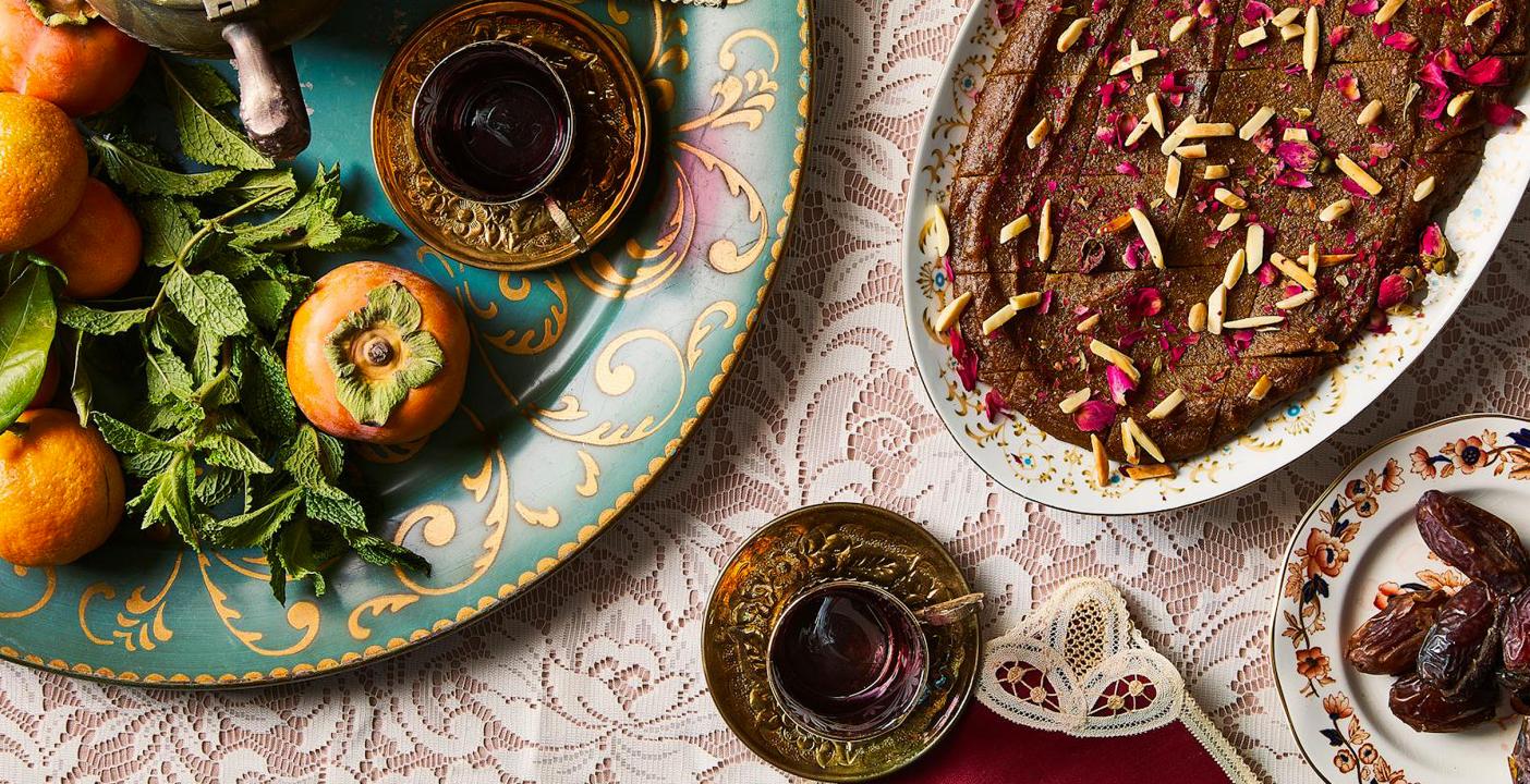 Persian food is displayed on plates on a tables covered in white lace.