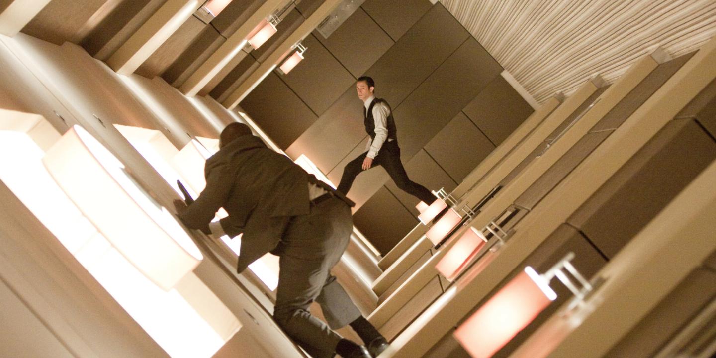 Still from the film Inception showing two men walking through a rotating hallway.