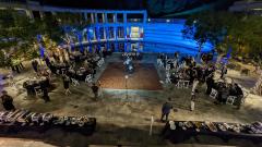 People dancing in an outdoor courtyard with a lily pond decorated with lights, tables, and a dance floor.