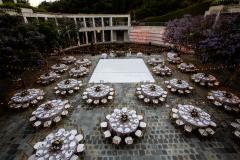 A couple dancing in an outdoor courtyard with a lily pond decorated with lights, tables, and a dance floor.