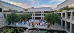 People at an outdoor courtyard with a lily pond decorated with rows of lights, tables, and a dance floor.