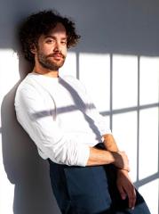 An artful photo of a man leaning against the wall outside.