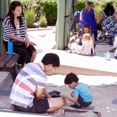 A family with kids digging through a sand box uncovering replica artifacts