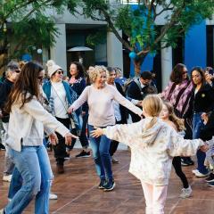 A large group of people dancing in a circle smiling.