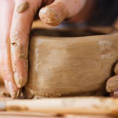 Hands craft a clay bowl.